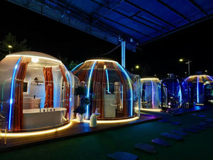 Dome pods at night with luxurious interiors, offering a high-end glamping experience.