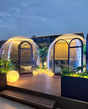 Illuminated transparent pods on a wooden deck at night, offering a luxurious glamping experience with ambient lighting at Nurture Pod - Earth Haven.