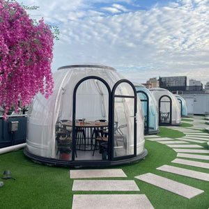 Transparent rooftop pods with seating area and a vibrant floral display, perfect for an outdoor dining or relaxation experience at Nurture Pod XL - Earth Haven.