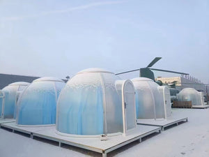 Snow-covered transparent pods in a winter setting, offering a unique cold-weather glamping experience.