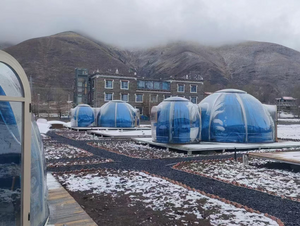 Snow-covered outdoor bubble pods with a scenic mountain backdrop, offering a unique winter glamping experience at Nurture Pod XL - Earth Haven.